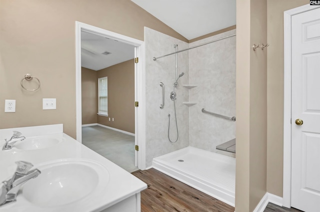 bathroom featuring hardwood / wood-style flooring, walk in shower, lofted ceiling, and sink