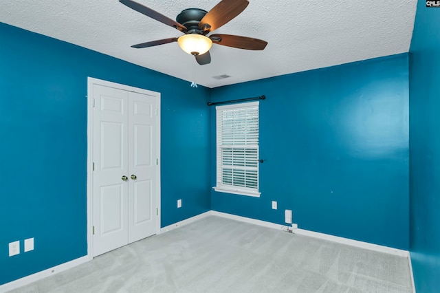 carpeted spare room featuring ceiling fan and a textured ceiling