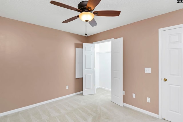 unfurnished bedroom with a textured ceiling, light colored carpet, and ceiling fan