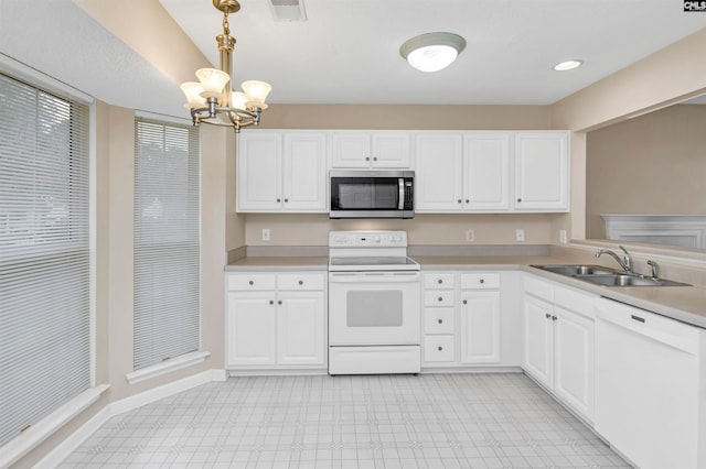 kitchen with white cabinetry, sink, hanging light fixtures, and white appliances