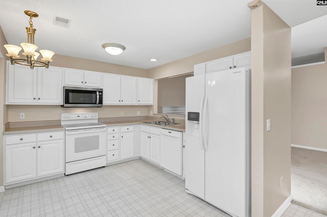 kitchen featuring white cabinets, white appliances, hanging light fixtures, and sink