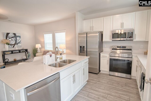 kitchen featuring white cabinets, sink, an island with sink, appliances with stainless steel finishes, and light hardwood / wood-style floors