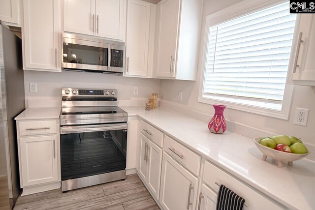 kitchen with white cabinetry, stainless steel appliances, and light hardwood / wood-style floors