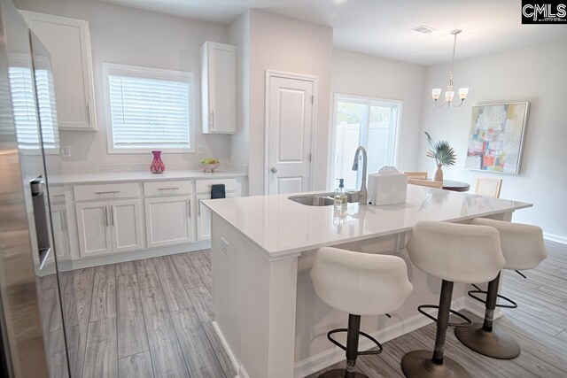 kitchen featuring white cabinets, decorative light fixtures, a wealth of natural light, and light hardwood / wood-style floors