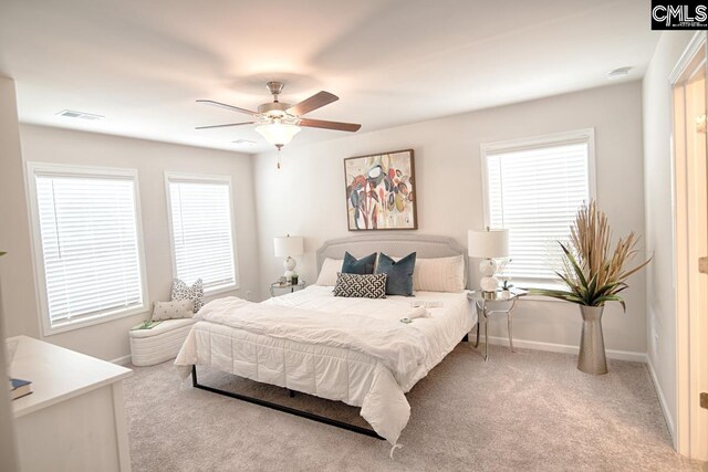 bedroom featuring ceiling fan, light colored carpet, and multiple windows