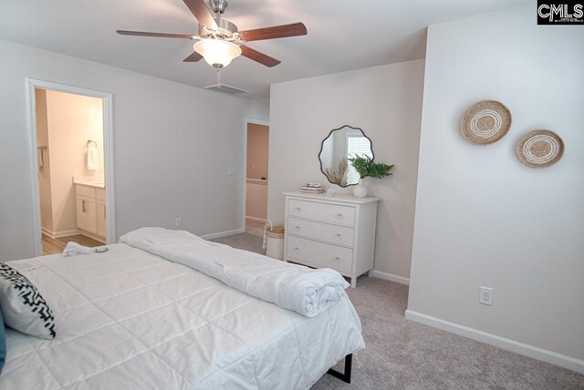 bedroom with ceiling fan, light colored carpet, and connected bathroom