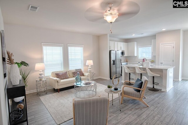 living room featuring ceiling fan, light hardwood / wood-style floors, and a wealth of natural light