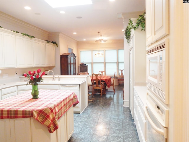 kitchen with white appliances, sink, hanging light fixtures, a skylight, and a notable chandelier