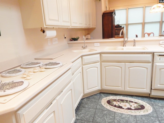 kitchen with dark tile patterned flooring, pendant lighting, white cabinetry, and sink