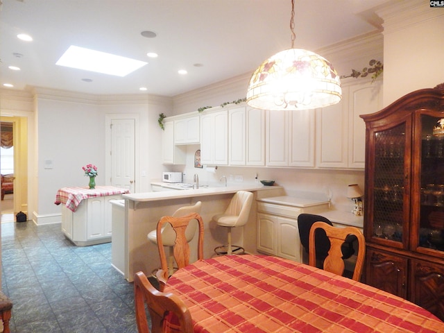 dining area featuring a skylight, sink, and ornamental molding