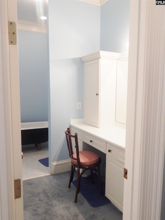 carpeted home office with built in desk and crown molding