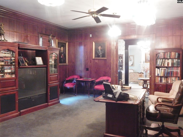 carpeted home office with ceiling fan, wood walls, and crown molding