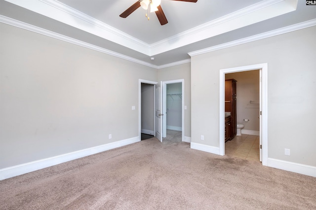 unfurnished bedroom with light carpet, ensuite bathroom, ceiling fan, a spacious closet, and ornamental molding