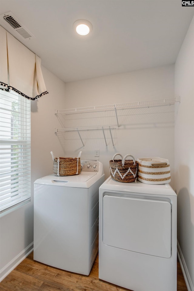 clothes washing area featuring washer and clothes dryer and wood-type flooring