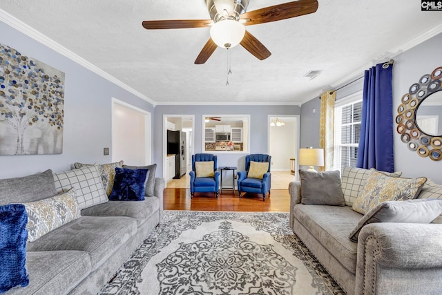 living room with crown molding, ceiling fan, a textured ceiling, and hardwood / wood-style flooring