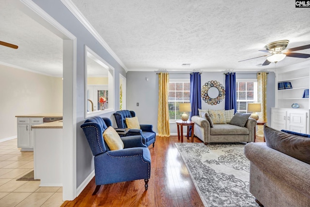 living room with a textured ceiling, light wood-type flooring, ceiling fan, and crown molding