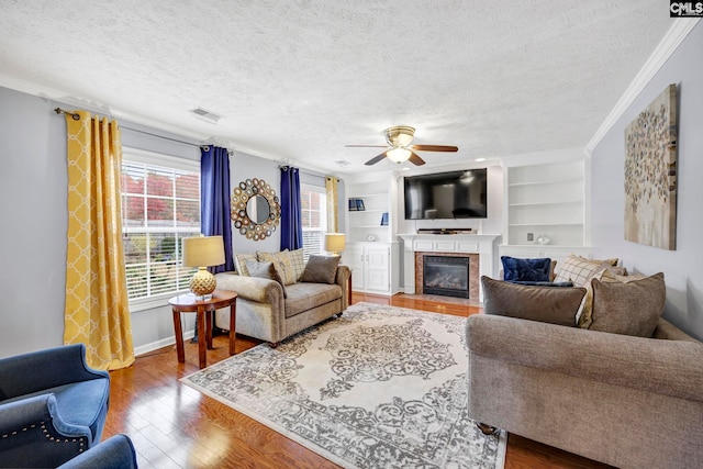 living room with hardwood / wood-style floors, a textured ceiling, ceiling fan, and ornamental molding