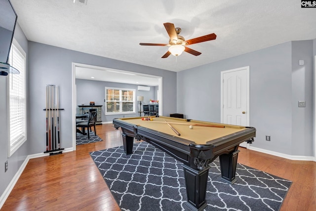 recreation room with a wall mounted air conditioner, billiards, hardwood / wood-style flooring, ceiling fan, and a textured ceiling