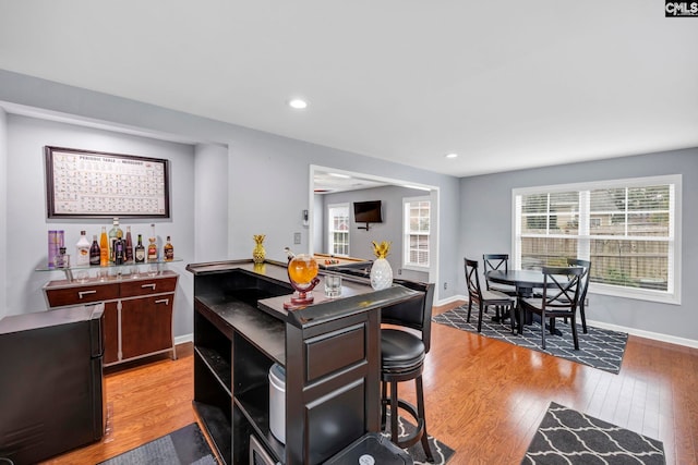 kitchen with dark brown cabinets, a kitchen island, a kitchen bar, and light hardwood / wood-style flooring