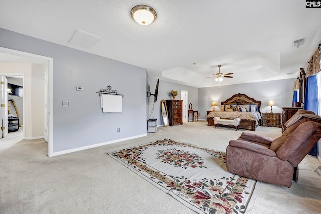 carpeted bedroom with ceiling fan and a tray ceiling