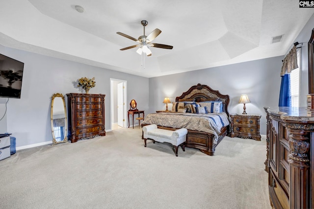 carpeted bedroom featuring a raised ceiling and ceiling fan