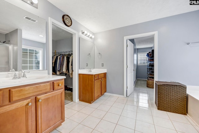 bathroom featuring tile patterned flooring, vanity, a textured ceiling, and a wealth of natural light