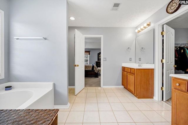 bathroom featuring tile patterned flooring, vanity, a bath, and a textured ceiling