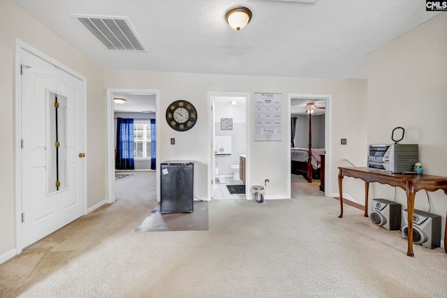 interior space with ceiling fan, light colored carpet, and a textured ceiling