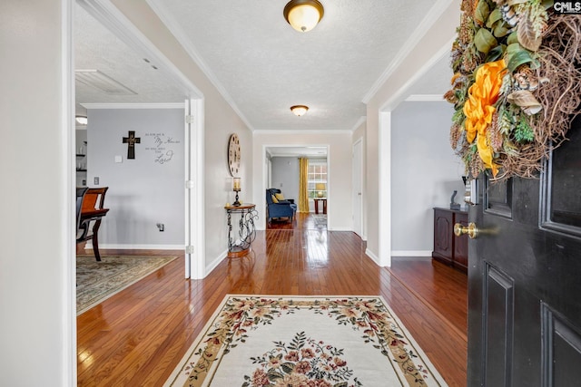 entryway with a textured ceiling, wood-type flooring, and crown molding