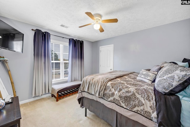 carpeted bedroom with ceiling fan and a textured ceiling