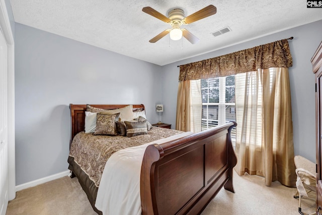 carpeted bedroom featuring ceiling fan and a textured ceiling