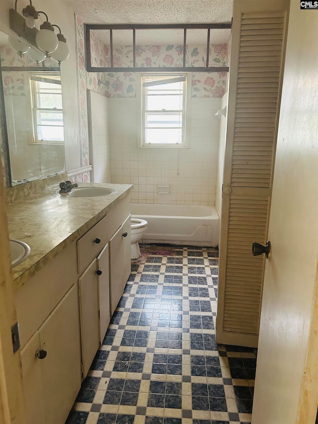 full bathroom with vanity, a healthy amount of sunlight, toilet, and a textured ceiling