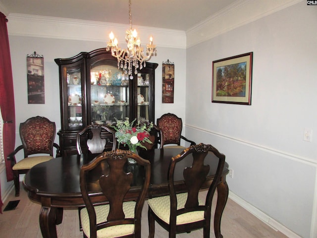 dining space with light hardwood / wood-style floors, an inviting chandelier, and crown molding