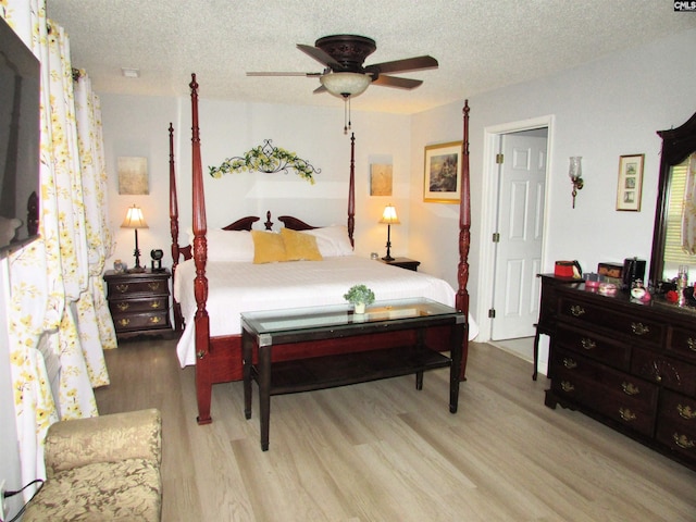 bedroom with ceiling fan, light wood-type flooring, and a textured ceiling