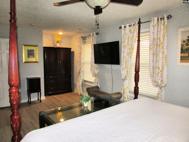 bedroom with a textured ceiling, hardwood / wood-style flooring, and ceiling fan