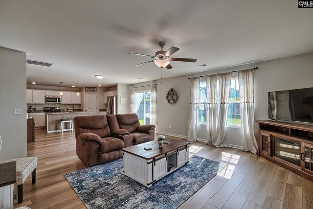 living room featuring light wood-type flooring and ceiling fan