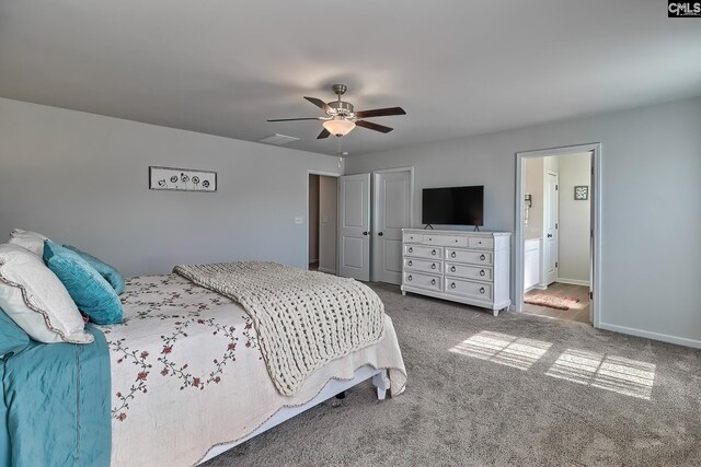 bedroom with ceiling fan, light colored carpet, and ensuite bath