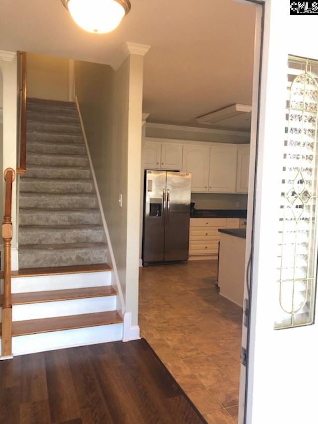 staircase with wood-type flooring and crown molding