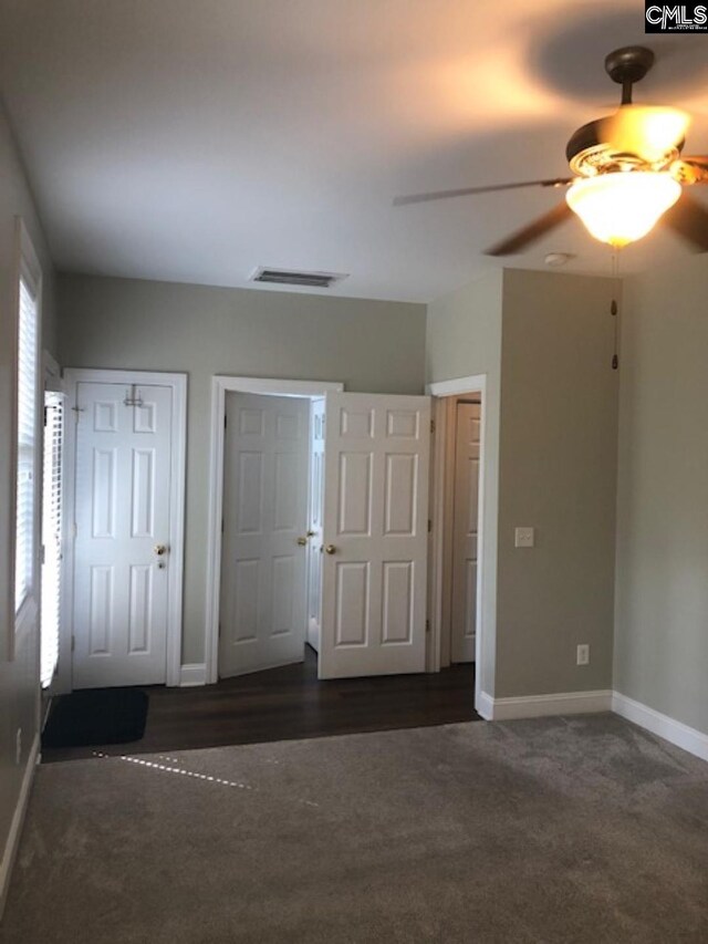 unfurnished bedroom with dark carpet and ceiling fan