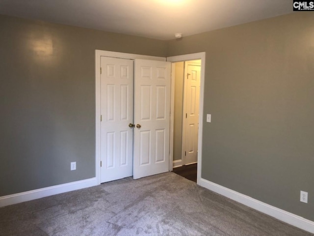 unfurnished bedroom with dark carpet and a closet