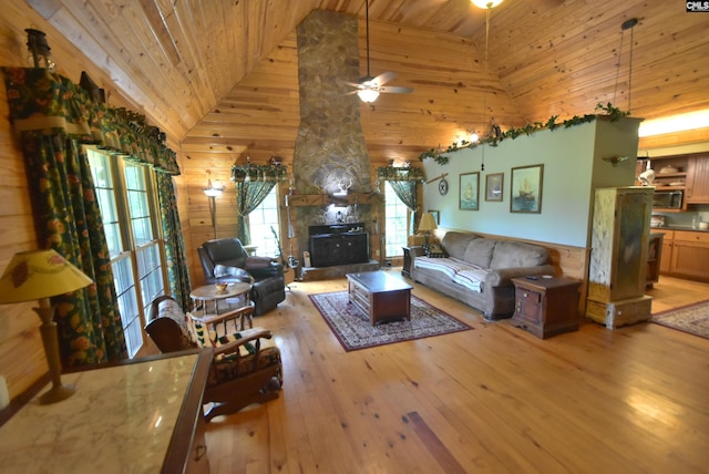 living room featuring wood walls, high vaulted ceiling, ceiling fan, light wood-type flooring, and wood ceiling