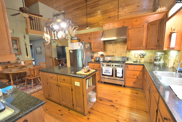 kitchen featuring appliances with stainless steel finishes, light wood-type flooring, extractor fan, pendant lighting, and a kitchen island