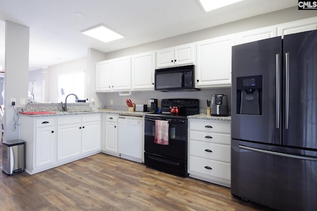 kitchen with sink, light stone counters, dark hardwood / wood-style floors, white cabinets, and black appliances