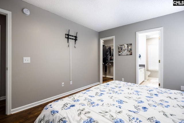 bedroom with ensuite bath, dark wood-type flooring, a textured ceiling, a walk in closet, and a closet