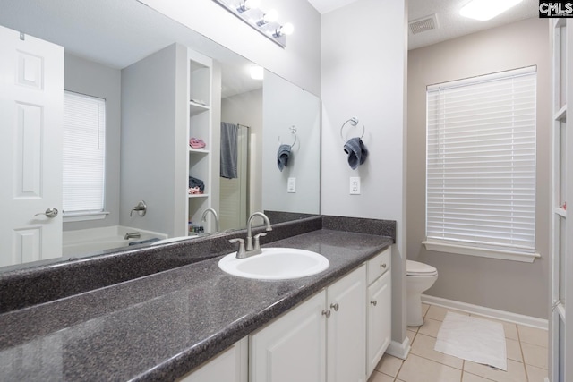 bathroom featuring tile patterned floors, vanity, toilet, and a bathing tub