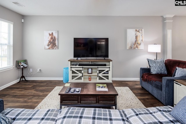 living room with plenty of natural light, dark hardwood / wood-style floors, and decorative columns