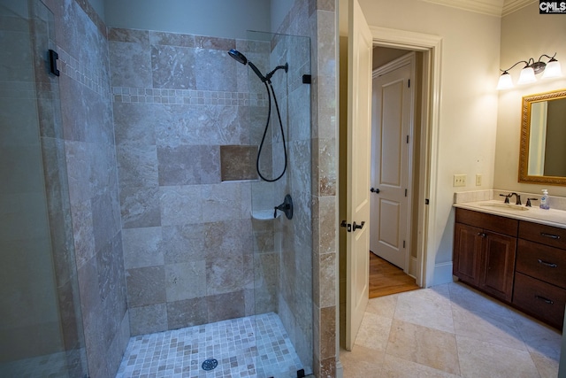 bathroom featuring a tile shower, vanity, and ornamental molding