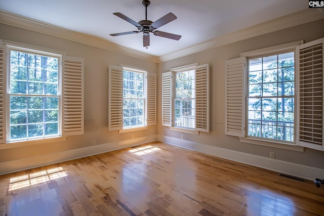 empty room with plenty of natural light, ornamental molding, and light wood-type flooring