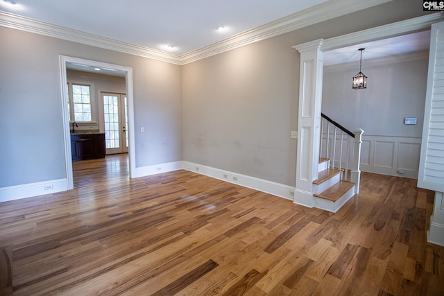 empty room with wood-type flooring, an inviting chandelier, and crown molding