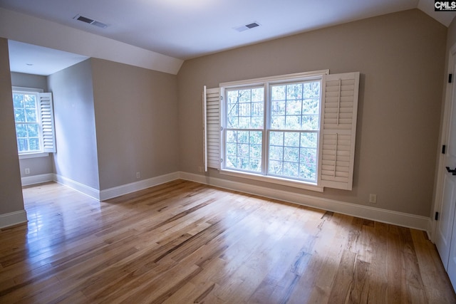 spare room featuring light hardwood / wood-style flooring and lofted ceiling